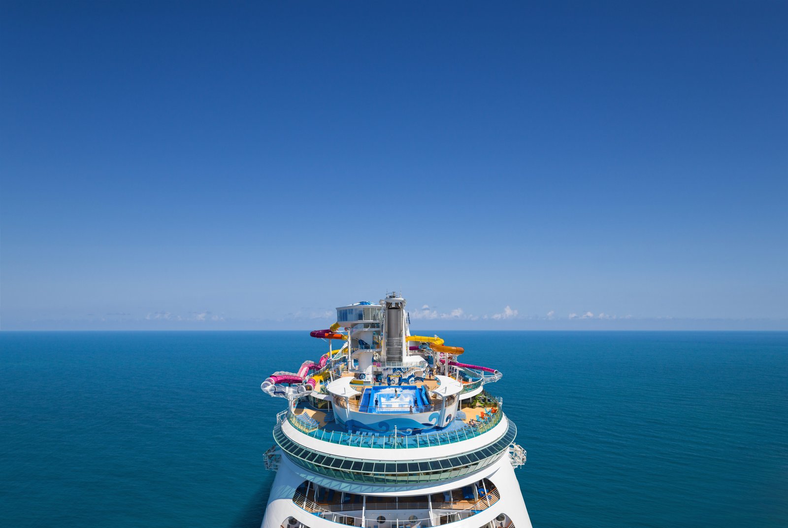Navigator of the Seas seen from the air along her centreline, waterslides and surf simulator on the upper decks, open sea all around